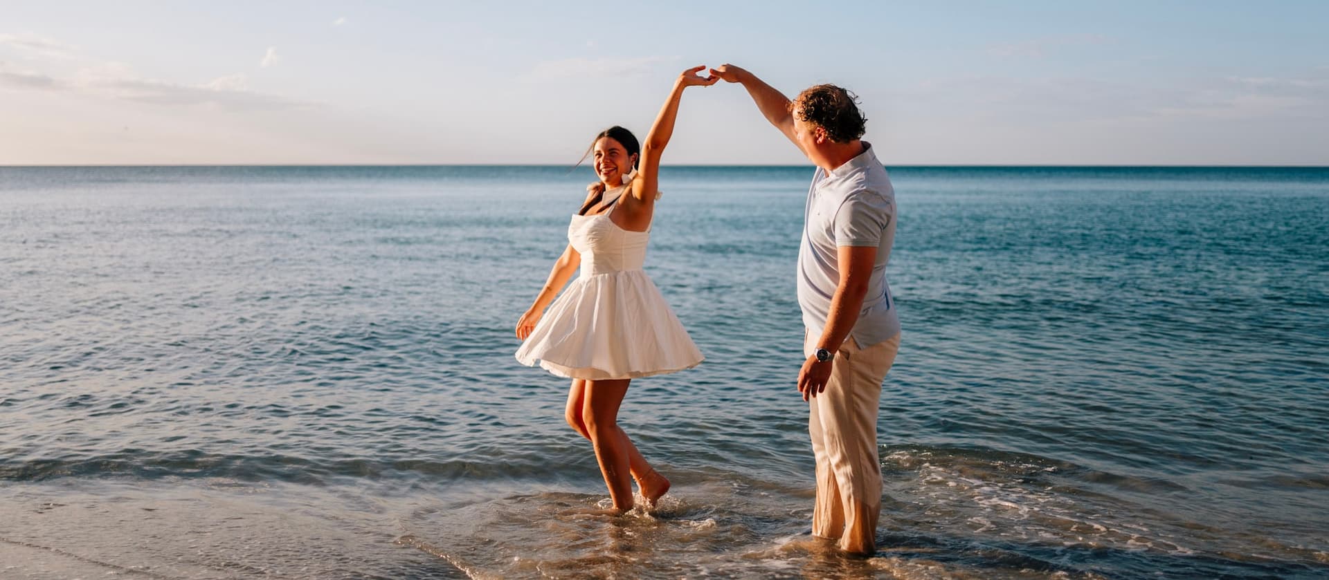 Couple dancing on the shore at sunset, golden hour