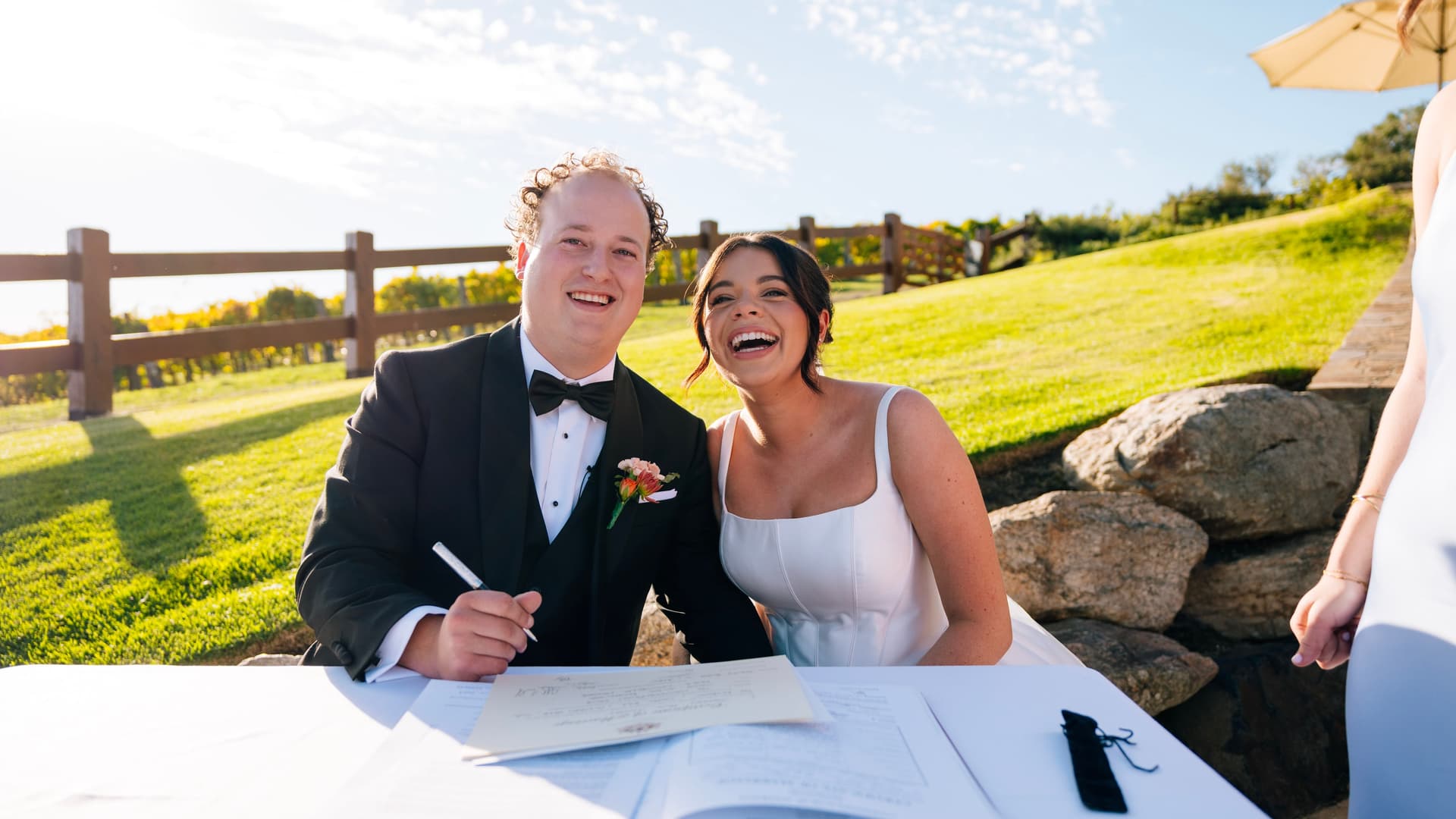 Couple sharing a joyous moment at the outdoor signing table, golden afternoon light